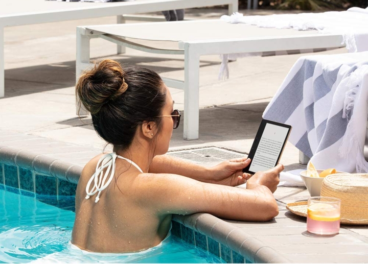 زنی در حالی که در یک استخر شنا است، کتاب الکترونیکی را در آمازون Kindle Oasis می خواند.