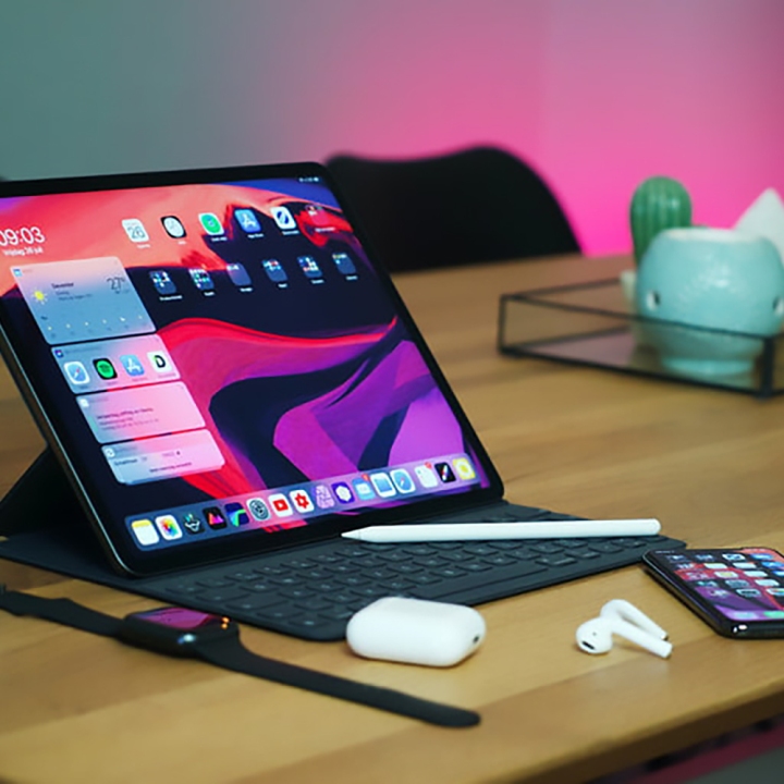 iPad Pro روی میز با AirPods و iPhone در نزدیکی.