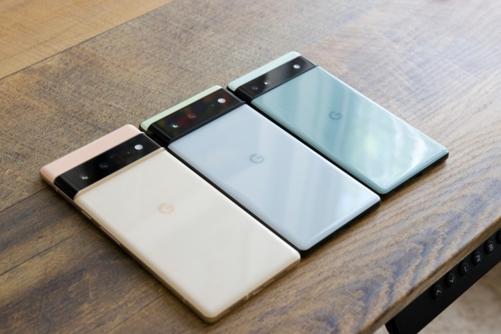 Google Pixel 6 Pro، Pixel 6 و Pixel 6a روی یک میز چوبی چیده شده اند.