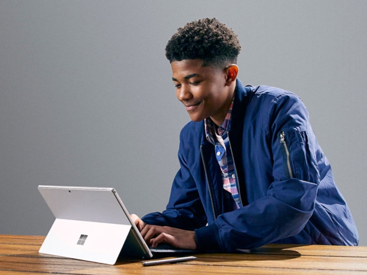 دانش آموزی از مایکروسافت سرفیس پرو 7 روی میزی با پوشش تایپ استفاده می کند.